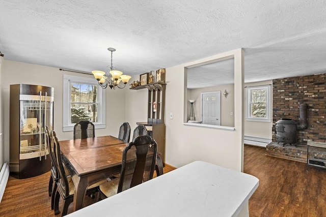 dining area with a chandelier, a wealth of natural light, dark wood-type flooring, and a textured ceiling