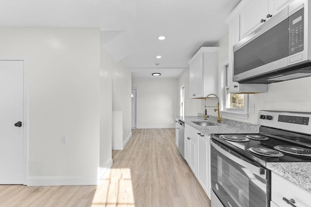 kitchen featuring stainless steel appliances, light wood-type flooring, light stone countertops, white cabinets, and sink