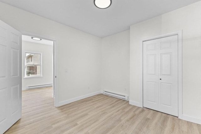 empty room featuring a baseboard radiator and light hardwood / wood-style flooring