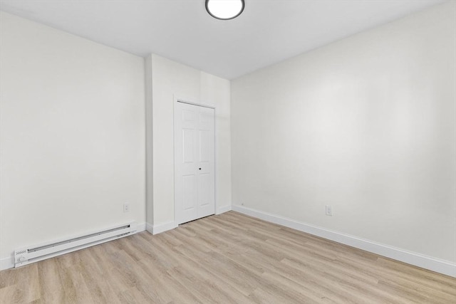 spare room featuring a baseboard heating unit and light hardwood / wood-style flooring