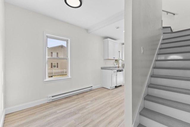 staircase with baseboard heating, hardwood / wood-style floors, and a healthy amount of sunlight