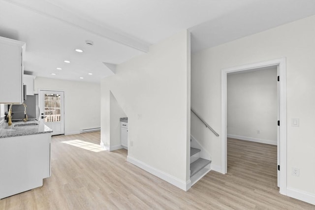 kitchen featuring white cabinets, light stone countertops, sink, and light hardwood / wood-style flooring