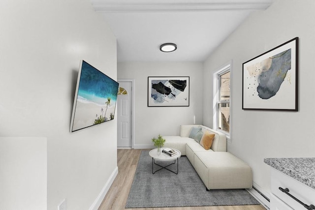 living area featuring light hardwood / wood-style floors and beamed ceiling