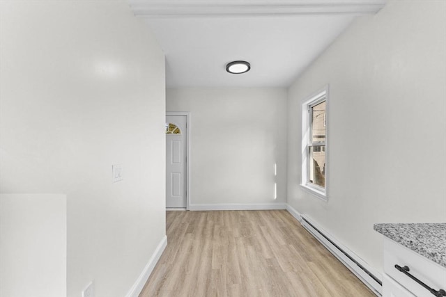 interior space with light wood-type flooring, beamed ceiling, and a baseboard radiator