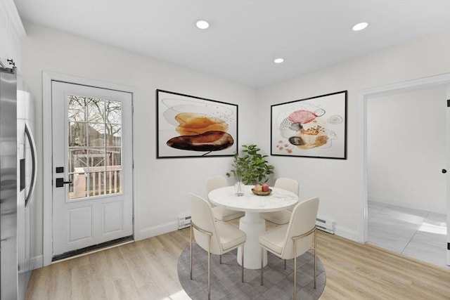 dining area with light wood-type flooring and a baseboard heating unit