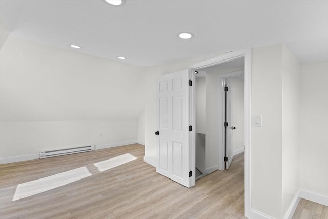 additional living space with baseboard heating, lofted ceiling, and light wood-type flooring