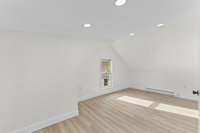 bonus room with a baseboard heating unit, vaulted ceiling, and light hardwood / wood-style flooring