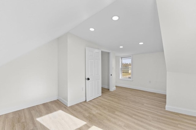 additional living space with vaulted ceiling and light hardwood / wood-style flooring