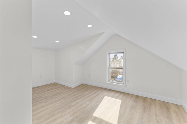 additional living space featuring vaulted ceiling and light hardwood / wood-style flooring