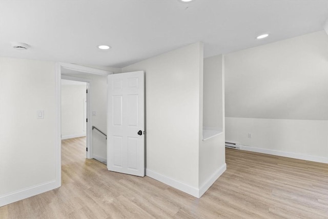 interior space featuring vaulted ceiling, a baseboard heating unit, and light hardwood / wood-style flooring