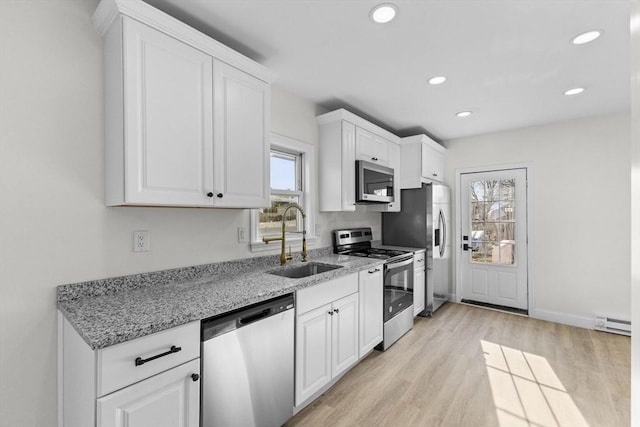 kitchen with white cabinets, appliances with stainless steel finishes, sink, and light stone counters