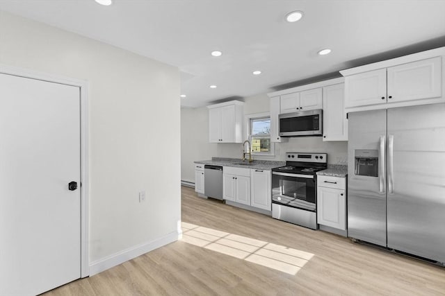 kitchen with sink, light wood-type flooring, appliances with stainless steel finishes, white cabinets, and light stone counters