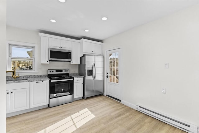 kitchen with a baseboard radiator, white cabinets, appliances with stainless steel finishes, and light wood-type flooring