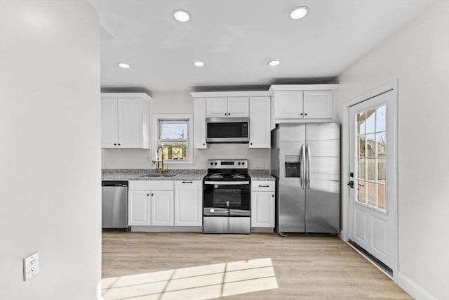 kitchen with a wealth of natural light, stainless steel appliances, white cabinets, and sink