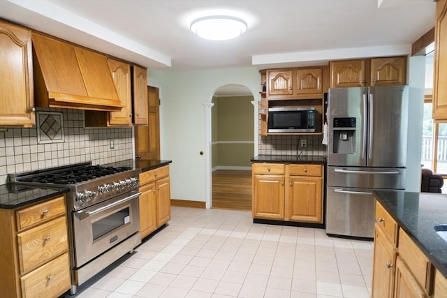118 Dudley Ln, Milton, MA 02186 - kitchen with stainless steel appliances, custom exhaust hood, arched walkways, decorative backsplash, and light tile patterned flooring