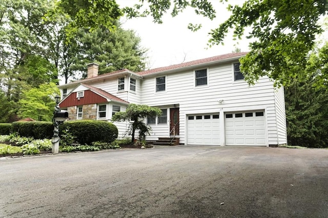 118 Dudley Ln, Milton, MA 02186 - view of front of house featuring asphalt driveway, a chimney, a garage, and stone siding