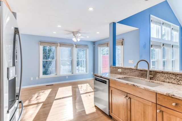 kitchen featuring sink, light hardwood / wood-style flooring, ceiling fan, light stone counters, and stainless steel appliances