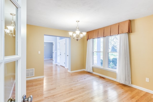 spare room with light hardwood / wood-style floors and a notable chandelier