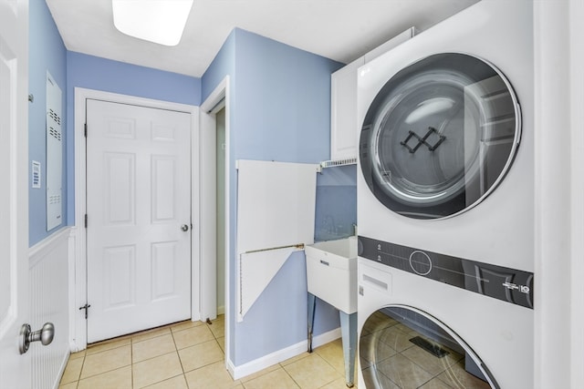 laundry area with light tile patterned floors and stacked washer and clothes dryer