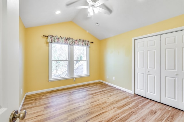 unfurnished bedroom featuring vaulted ceiling, a closet, light hardwood / wood-style flooring, and ceiling fan