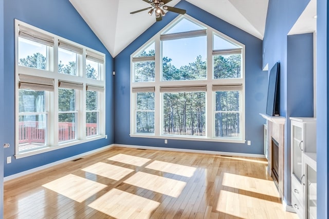 unfurnished living room with light hardwood / wood-style floors, high vaulted ceiling, ceiling fan, and a healthy amount of sunlight