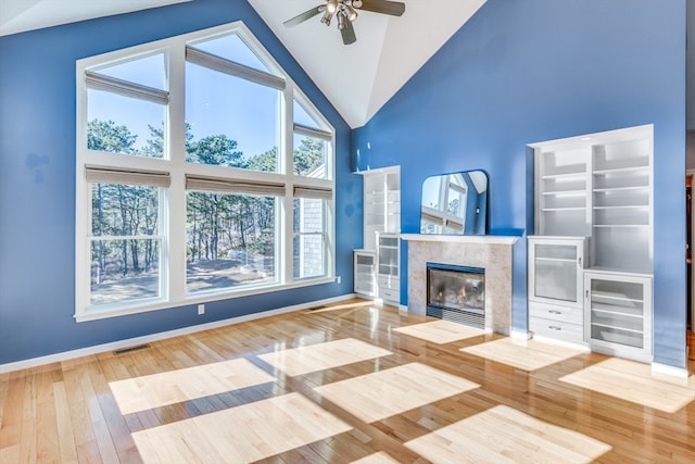 unfurnished living room with hardwood / wood-style flooring, high vaulted ceiling, ceiling fan, and a premium fireplace