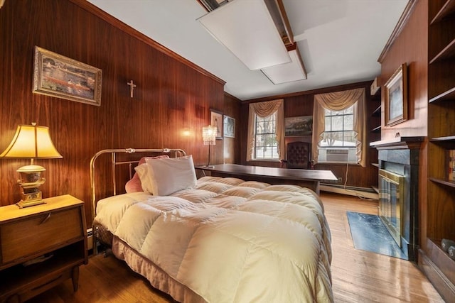 bedroom featuring a fireplace, wooden walls, and a baseboard radiator