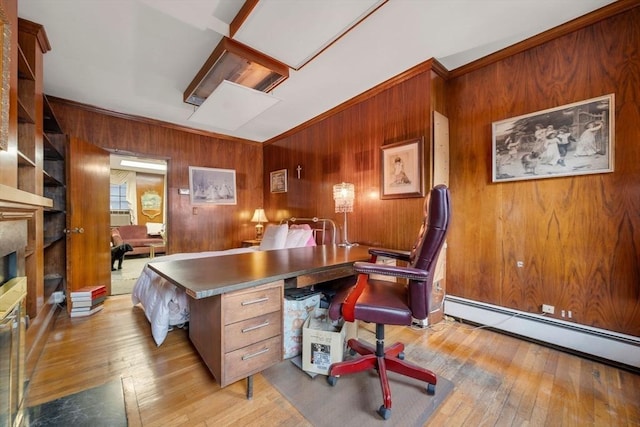 office area featuring baseboard heating, ornamental molding, light hardwood / wood-style floors, and wood walls