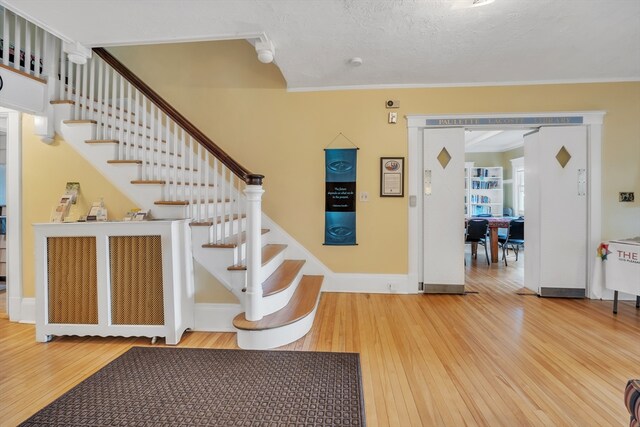 stairway with wood-type flooring, a textured ceiling, and ornamental molding