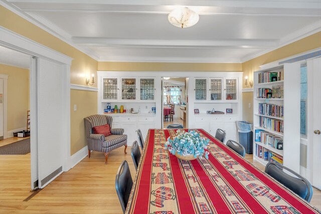 bedroom featuring beamed ceiling, crown molding, and light wood-type flooring