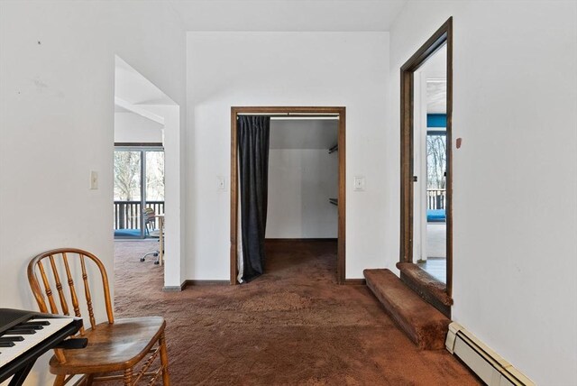 hall featuring dark colored carpet, a baseboard radiator, and baseboards