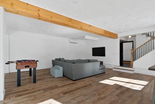 living room with stairs, wood finished floors, beam ceiling, and baseboards