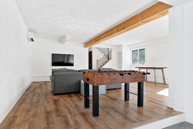 rec room with baseboards, beamed ceiling, and wood finished floors