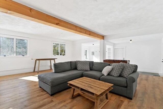 living area featuring light wood-style floors, beam ceiling, and baseboards