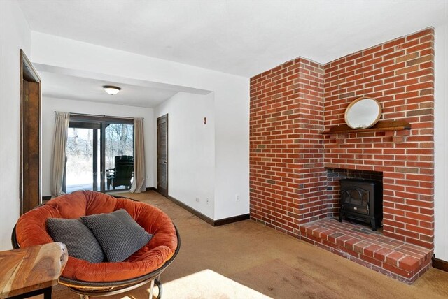 living room featuring baseboards, a wood stove, and light colored carpet