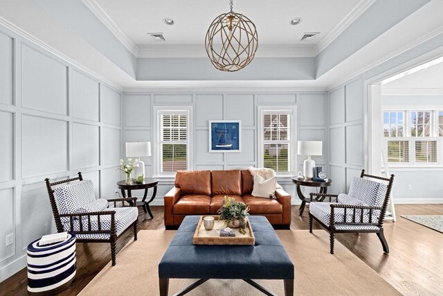 90 Chittenden Ln Unit 90, Cohasset, MA 02025 - living room featuring a decorative wall, wood finished floors, a tray ceiling, crown molding, and a chandelier