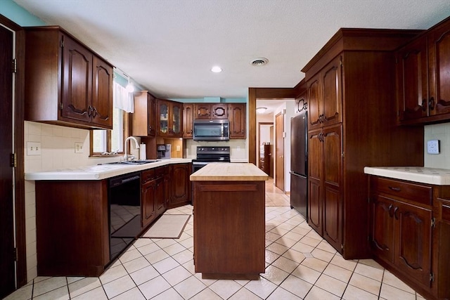 kitchen with stainless steel appliances, a sink, a center island, glass insert cabinets, and recessed lighting