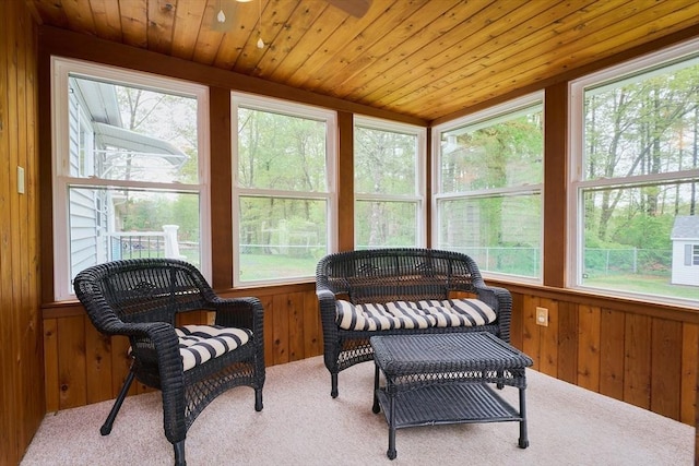 sunroom featuring carpet, wooden walls, healthy amount of natural light, and wood ceiling