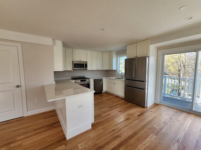 kitchen with plenty of natural light, white cabinetry, kitchen peninsula, and stainless steel appliances