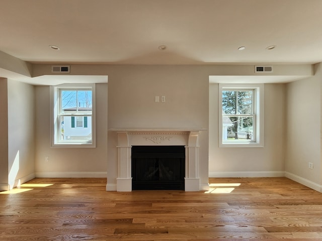 unfurnished living room featuring plenty of natural light and light hardwood / wood-style floors