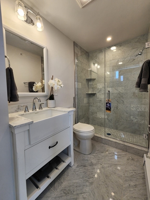 bathroom featuring vanity, toilet, a shower with door, and a baseboard heating unit