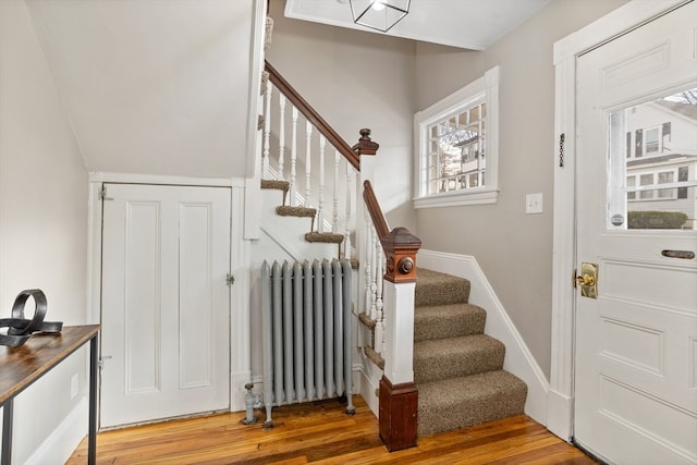 staircase with wood-type flooring and radiator heating unit