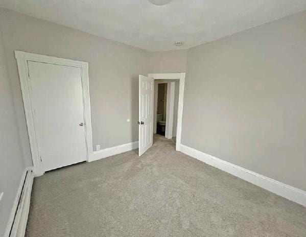 unfurnished bedroom featuring carpet, a baseboard heating unit, and baseboards