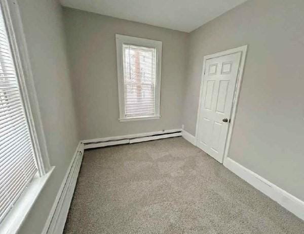 spare room featuring carpet, a baseboard radiator, and baseboards