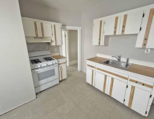 kitchen with baseboards, white cabinetry, white gas range, under cabinet range hood, and a sink