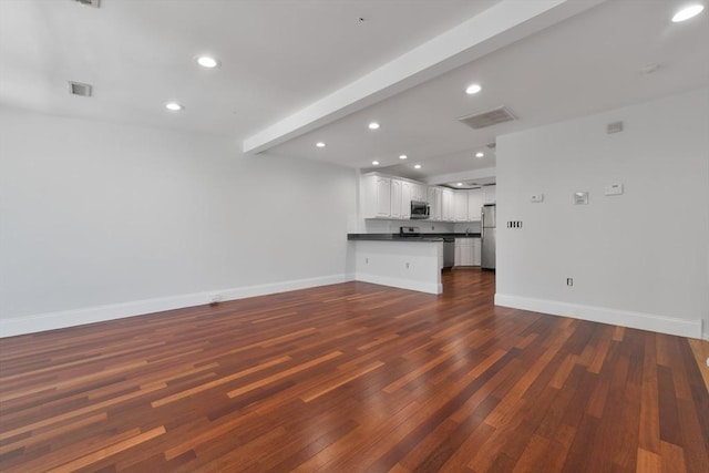 unfurnished living room with dark wood-type flooring and beam ceiling