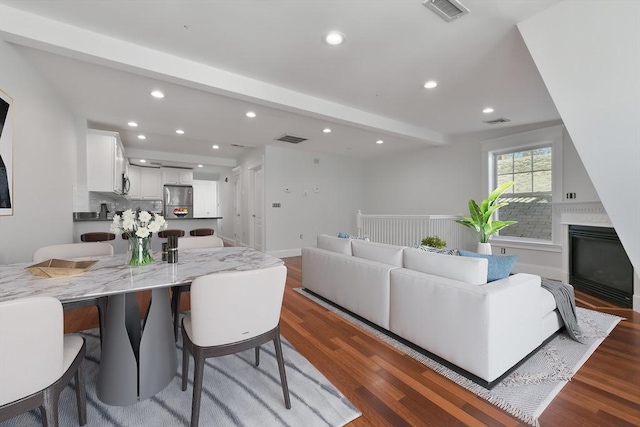 living room featuring beam ceiling and dark hardwood / wood-style floors