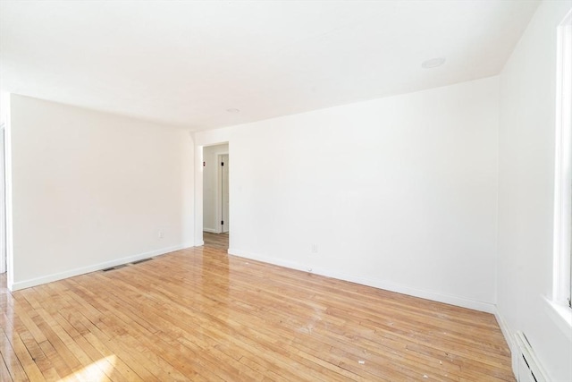 unfurnished room featuring light wood-style floors, a baseboard radiator, and baseboards