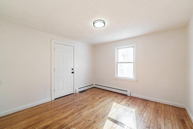 unfurnished room with baseboard heating, baseboards, and light wood finished floors