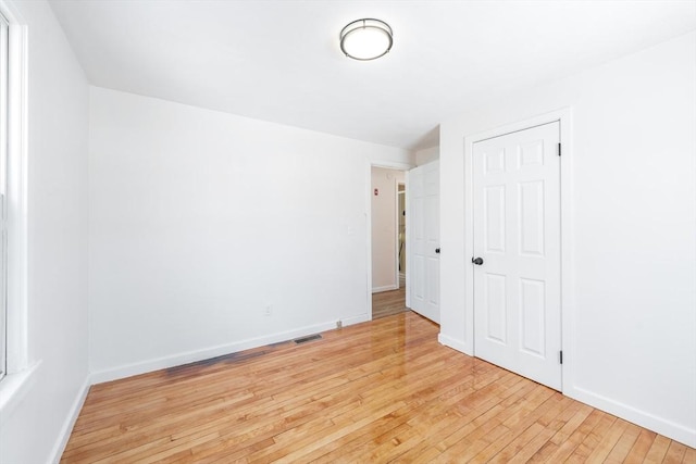 unfurnished bedroom featuring light wood-style floors, baseboards, and visible vents